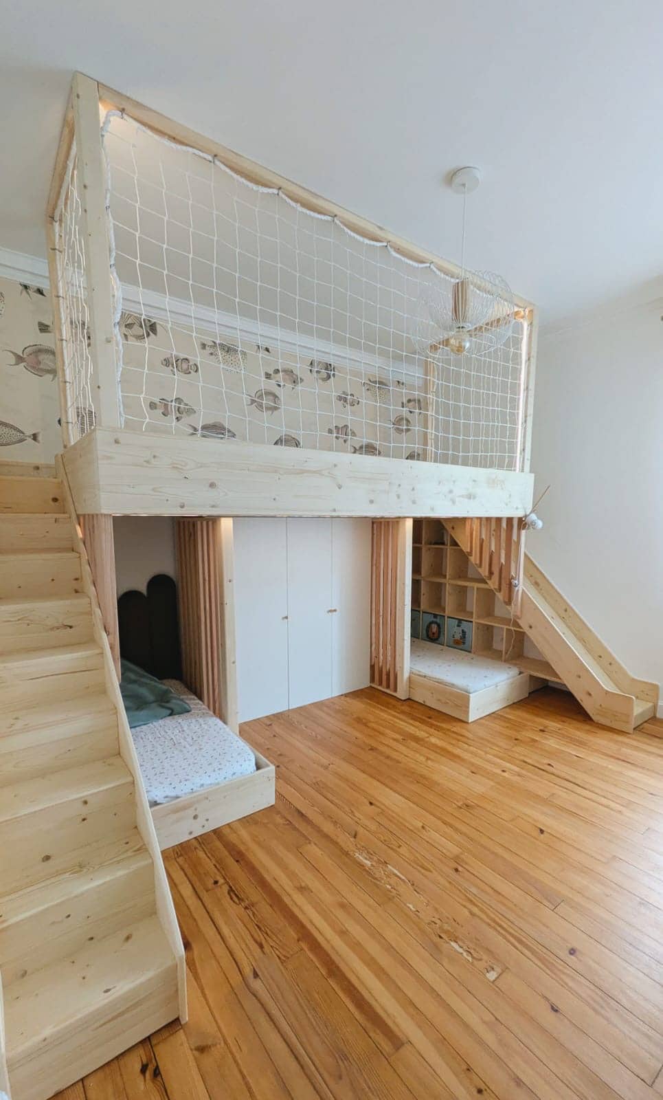 Lit mezzanine en bois avec escalier, toboggan et filet de protection dans une chambre d'enfant au thème marin.